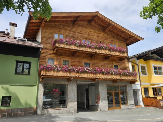 Fassade im Sommer mit Blumen an beiden Balkonen
