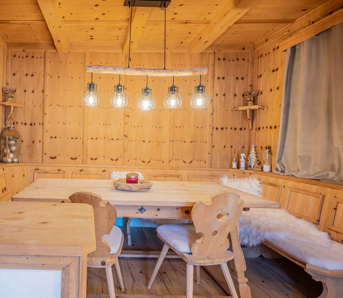 Holzvertäfelte Stube mit Eckbank, Esstisch, Fellen und Hängeleuchten